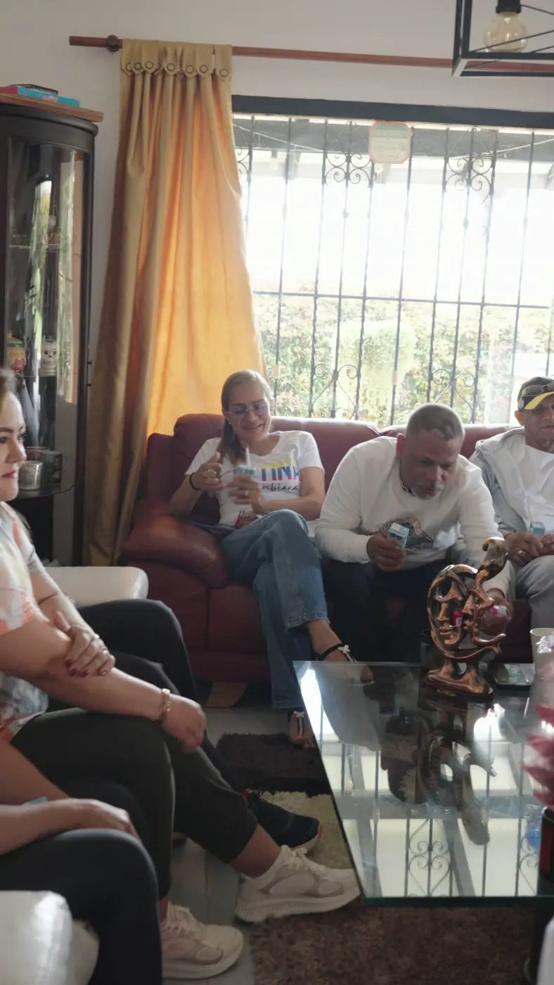 Participantes reunidos en la sala de la casa alrededor de una mesa de vidrio, al inicio del día