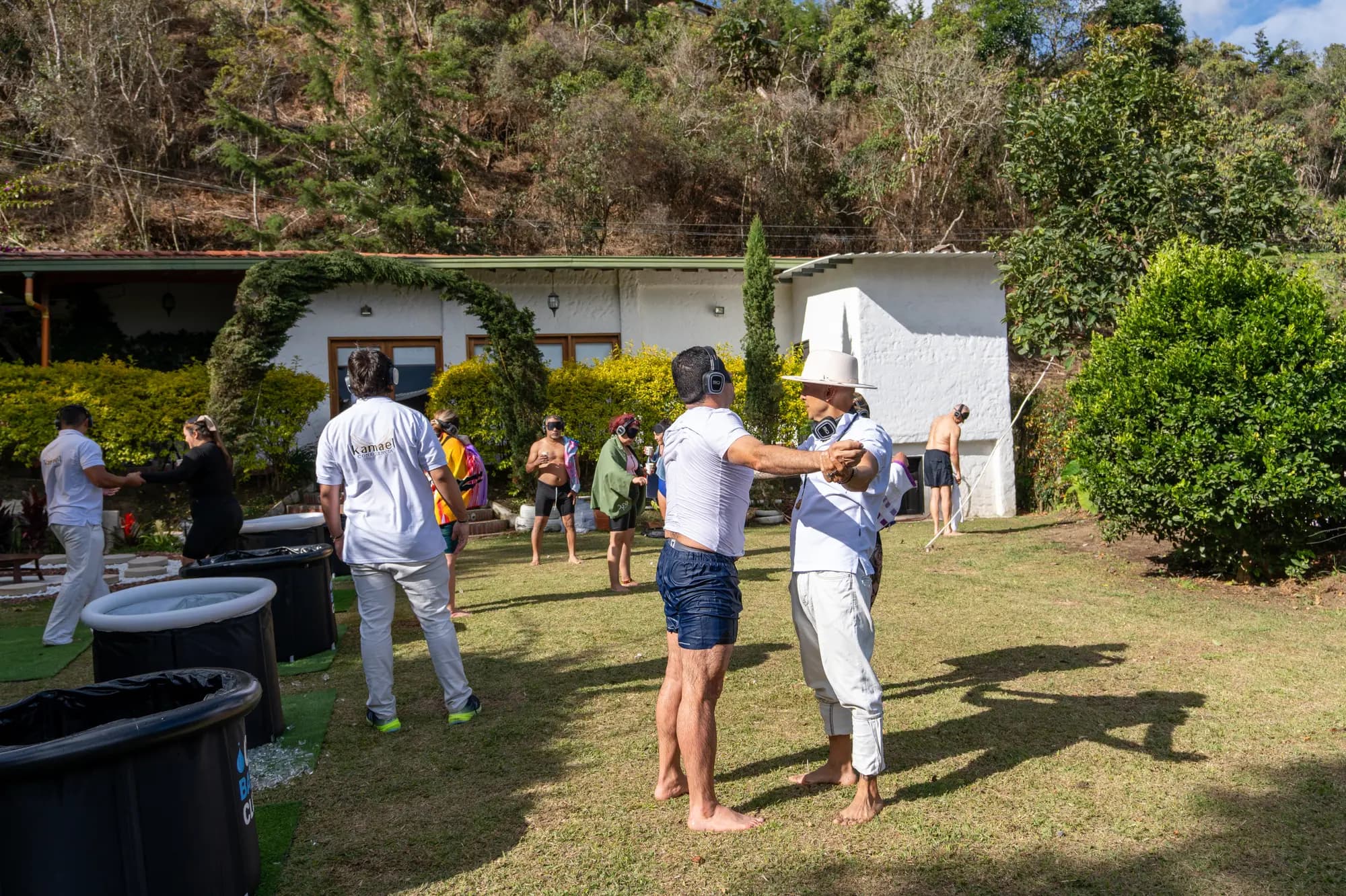 Jardines de Casa KAMAEL durante un taller, con acompañamiento a una participante y tinas de inmersión sobre el césped